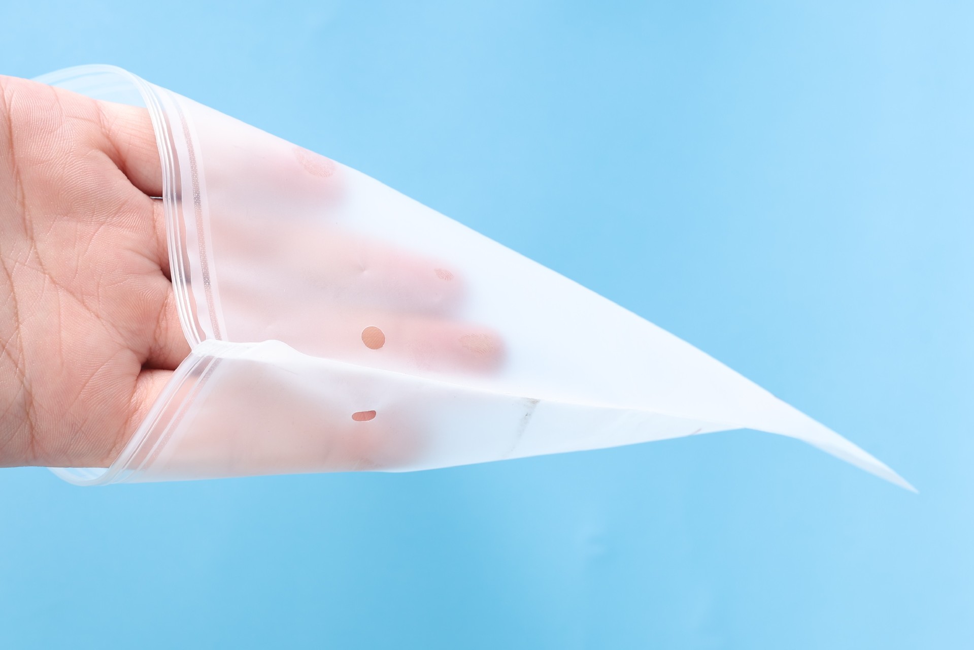 Clear PE zipper bag for apparel packaging being opened by hand